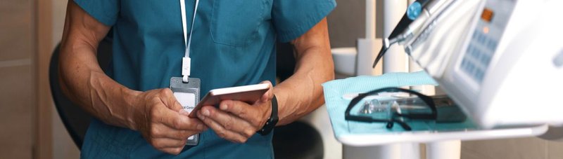 Hände eines Zahntechnikers am Smartphone